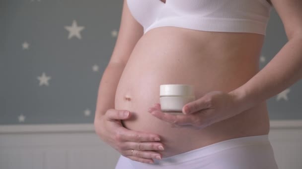 Zwangere vrouw met crème voor buik — Stockvideo