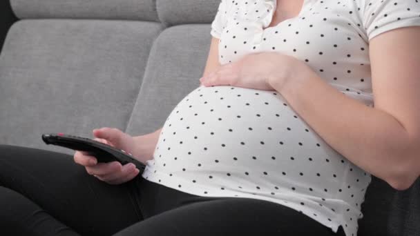 Gravid Kvinde Med Fjernbetjening Ser Mens Sidder Sofaen Derhjemme Ukendt – Stock-video