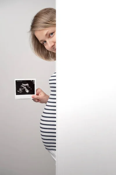 초음파 스캔을 임산부가 벽에서 있어요 임산부가 카메라를 초음파 사진을 주면서 — 스톡 사진