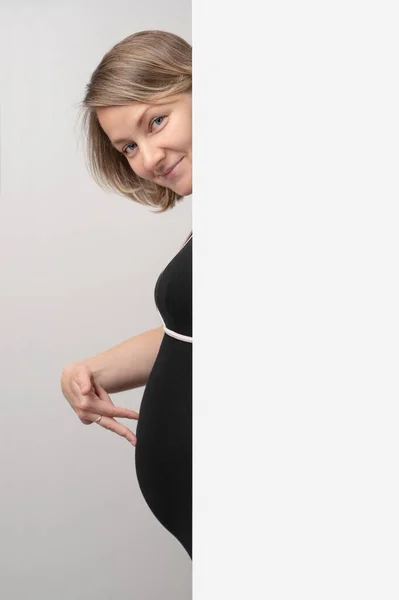 Mujer Embarazada Asomándose Por Pared Blanca Mujer Embarazada Feliz Tocando Fotos de stock