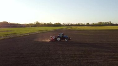Yay tarlasında mavi traktörün hava görüntüsü. Ekme için hazırlık zamanı. Traktörün üzerinde uçan bir dron ve ekin için hazırlanmış toprakla ateş etmek. Tarım konsepti. Kırsal alan.