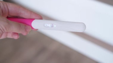 Kocasına hamilelik testi gösteren bir eş. Kadının erkeğe iki çizgili pozitif hamilelik testi yaptığı yakın çekim. Hamilelik konsepti, aile planlaması.