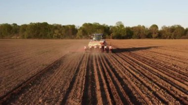 Yay tarlasında mavi traktörün hava görüntüsü. Ekme için hazırlık zamanı. Traktörün üzerinde uçan bir dron ve ekin için hazırlanmış toprakla ateş etmek. Tarım konsepti. Kırsal alan.