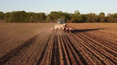 Yay tarlasında mavi traktörün hava görüntüsü. Ekme için hazırlık zamanı. Traktörün üzerinde uçan bir dron ve ekin için hazırlanmış toprakla ateş etmek. Tarım konsepti. Kırsal alan.