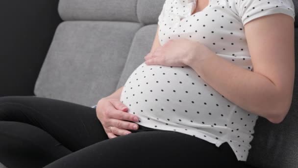 Happy Pregnant Belly Woman Prepares Baby Clothes While Sitting Sofa — Vídeos de Stock