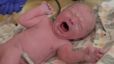 Screaming baby. Nurse take care of the newborn at hospital. Close up view of a tiny newborn child crying.