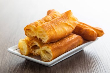 Youtiao (Çin usulü kızarmış ekmek). Uzun altın sarısı kızarmış hamur şeridi.