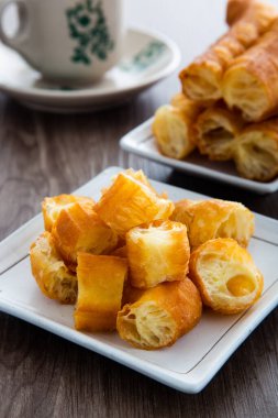 Youtiao (Çin usulü kızarmış ekmek). Uzun altın sarısı kızarmış hamur şeridi.