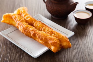 Youtiao (Çin usulü kızarmış ekmek). Uzun altın sarısı kızarmış hamur şeridi.