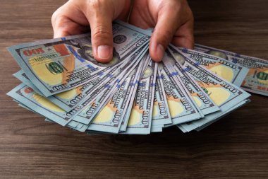 Kağıt para sayan bir adam. 100 dolarlık banknotlar ellerinde. Başarı ve zenginlik iş konsepti.