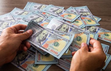 Kağıt para sayan bir adam. 100 dolarlık banknotlar ellerinde. Başarı ve zenginlik iş konsepti.