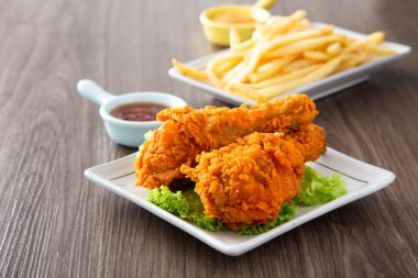 crispy and golden fried chickens with sauce on wooden table clipart