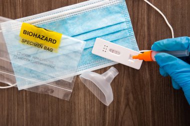 Mavi cerrahi eldivenli bir el, numuneyi covid-19 antijen test cihazına yerleştiriyor.