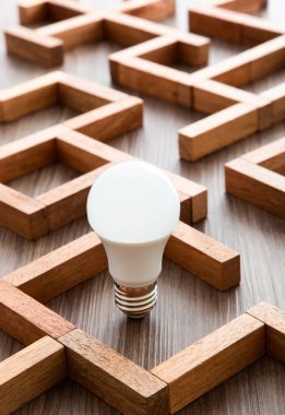 Light bulb in the maze game built by wood blocks, finding the right way to the success, searching creative idea concept clipart