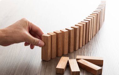 İşadamının eli kapanıyor. Tahta bloğu domino taşına yerleştiriyor..