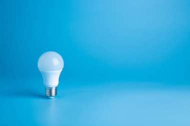 Pastel renklerde beyaz ampul mavi arka plan. Minimalist kavram, parlak fikir,