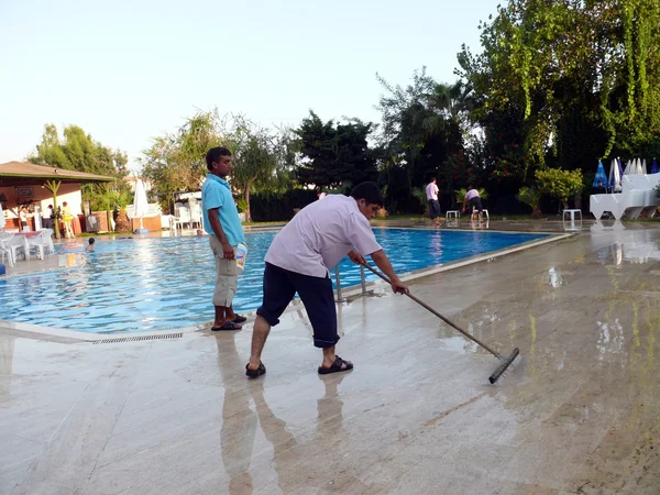 Alania, Türkei - 31. August 2008: Reinigungskraft wäscht den Boden in der Nähe des Swimmingpools am 31. August 2008 in alania, Türkei Stockbild