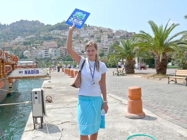 Alanya, Turkey - September 01, 2008: Representative of Tez Tour company awaits tourists near the yacht on September 01, 2008 in Alanya, Turkey Лицензионные Стоковые Изображения