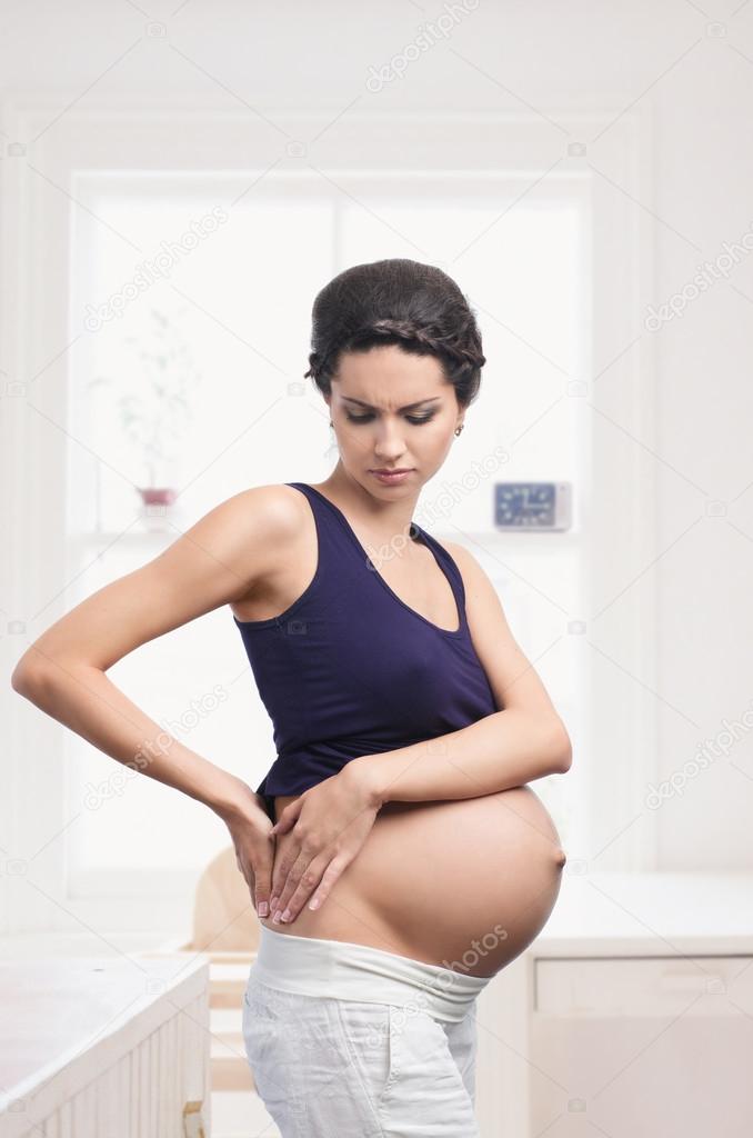 Pregnant woman standing with back pain at home