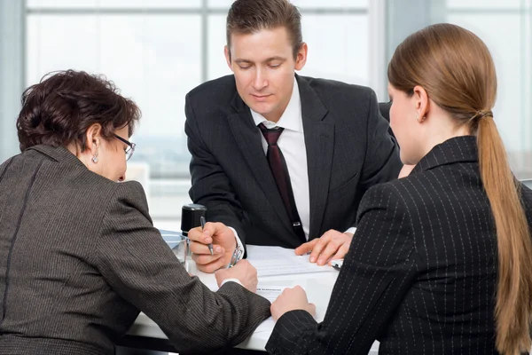 Agente firma documenti con un paio di donne — Foto Stock