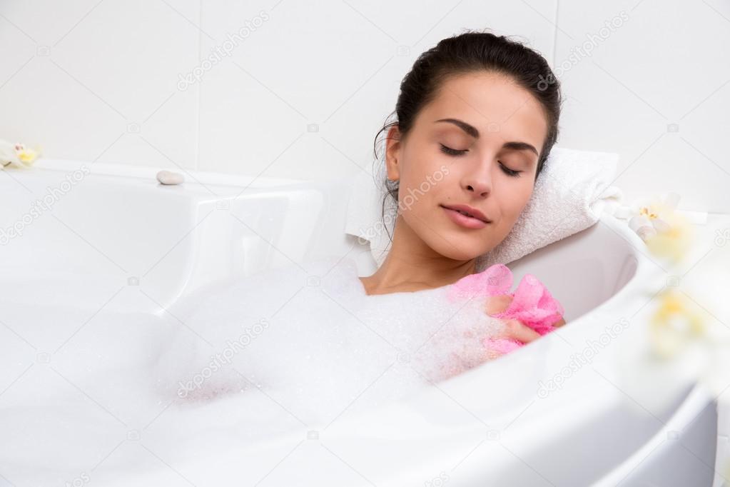 Beautiful young woman takes bubble bath