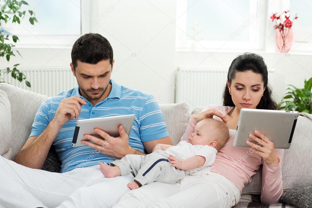 Family with baby sitting at home with a tablet PC