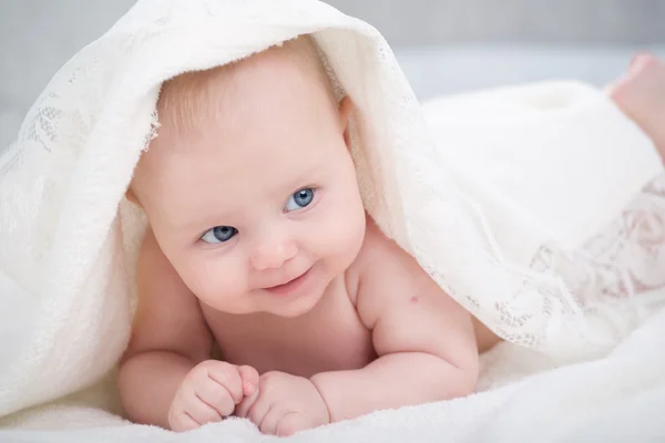 Baby kijken camera onder een witte deken — Stockfoto