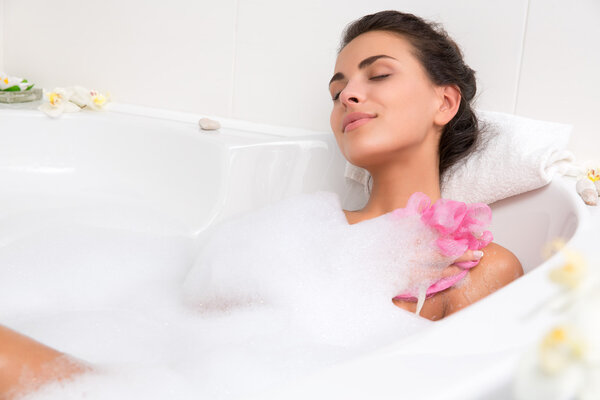 Beautiful young woman takes bubble bath