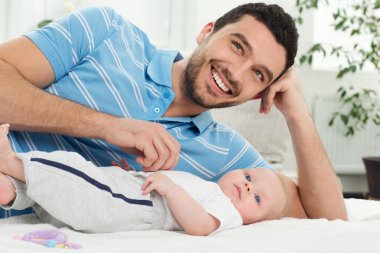 Happy father lies with a baby