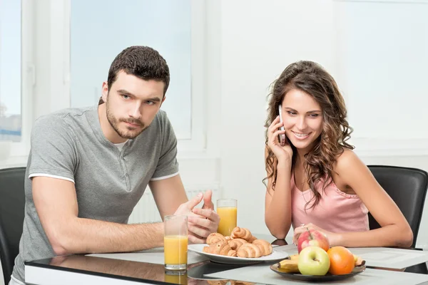 Пара завтракает, девушка разговаривает по телефону — стоковое фото