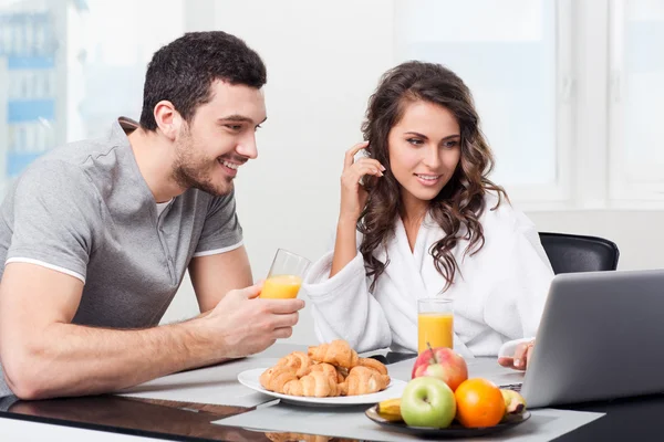 Bella coppia che fa colazione con un computer portatile — Foto Stock