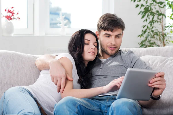 Пара сидить на дивані з планшетними комп'ютерами — стокове фото