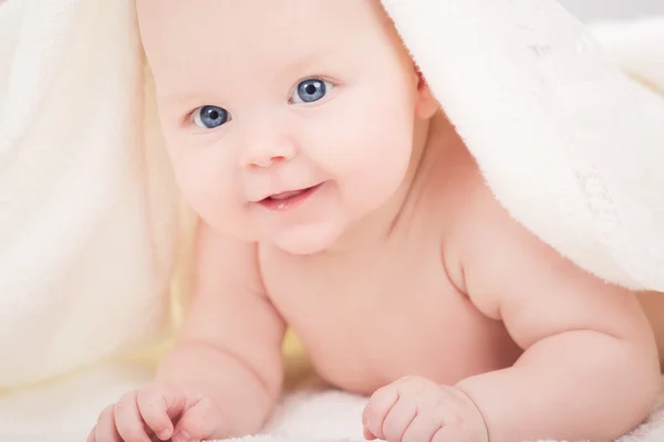 Малыш смотрит в камеру под белым одеялом — стоковое фото