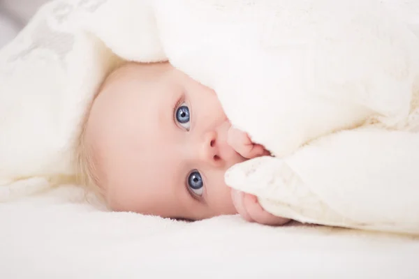 Baby looking at camera under a white blanket — Stock Photo, Image