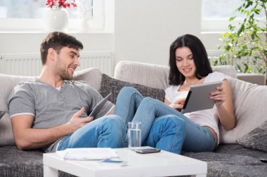 tablet bilgisayarlar ile bir kanepede oturan Çift