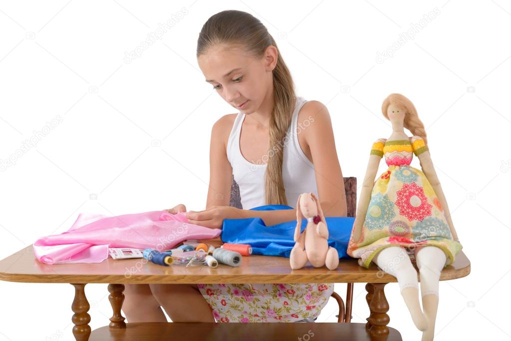 The girl sews toys from fabric