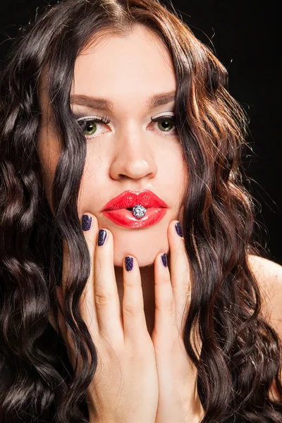 Mujer de moda sosteniendo una joya en los labios —  Fotos de Stock
