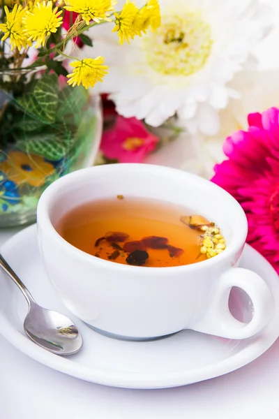 Šálek čaje s květiny na stole — Stock fotografie