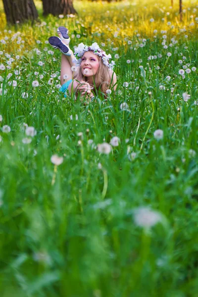 Молодая женщина, дующая одуванчик на полях — стоковое фото