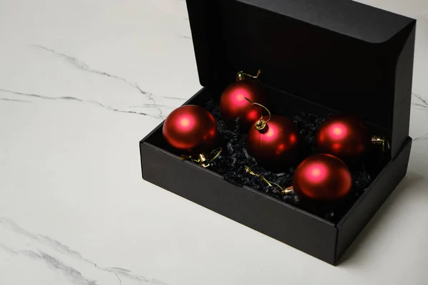 为圣诞节做准备圣诞树的装饰 白色大理石底座黑匣子里的红色圣诞球 — 图库照片