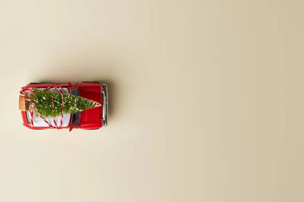 庆祝圣诞节或新年贺卡的最小设计 送礼的概念 浅色背景上的小红玩具车和圣诞树 — 图库照片