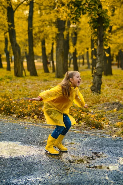 Ein Kleines Mädchen Gelbem Regenmantel Und Gelben Stiefeln Springt Einer — Stockfoto