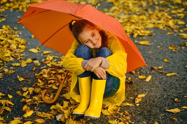 Bambina Seduta Sull Asfalto Sotto Ombrello Arancione Sotto Pioggia Divertimento — Foto Stock