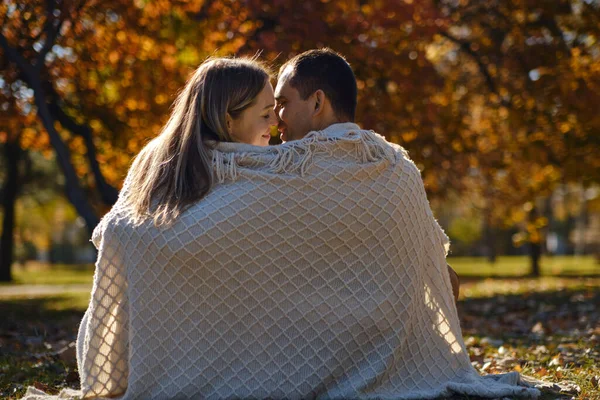 美しいカップルの男の愛の女性 秋の晴れた日に公園で一緒に抱き合うベージュの毛布に包まれた男と女 本物の人間 — ストック写真