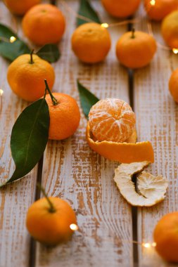 Mandalina portakalları, mandalinalar, mandalinalar, ahşap arka planda yaprakları olan narenciye meyveleri, çelenkli noel kompozisyonu
