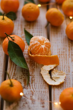 Mandalina portakalları, mandalinalar, mandalinalar, ahşap arka planda yaprakları olan narenciye meyveleri, çelenkli noel kompozisyonu