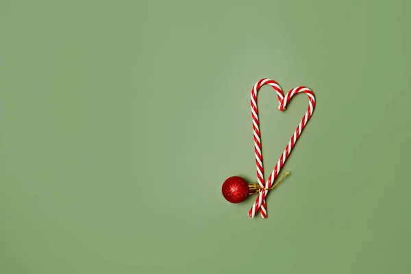 クリスマスカードの背景 お菓子や新年の装飾で作られたクリスマスツリーや心 最小限の休日の概念 緑の背景にキャンディケーンズと赤いおもちゃのボール フラットレイアウト トップビュー コピースペース — ストック写真