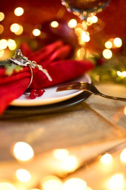 Geleneksel Noel masası kapanıyor. Altın çatal bıçak takımı, geyik yüzüklü keten peçete, ladin dalları. Tatil geçmişi. Seçici odak, çelenk, bokeh.