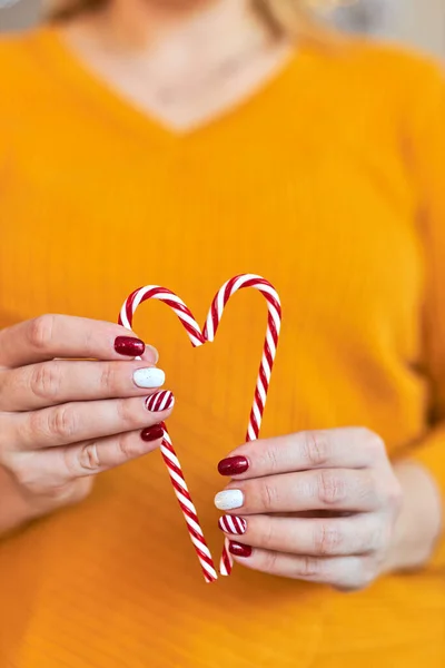 圣诞新年美甲抽象指甲设计 漂亮的修整过的女人手握着糖杖 心形的装饰品 — 图库照片
