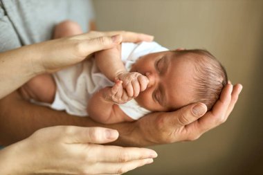 Ebeveynler yeni doğmuş bebek kafasını tutuyor. Annelik, babalık ya da ebeveynlik ve babalar günü konsepti. Modern ebeveynlik. Rahat ve güvenli bir uyku. İnsan sigortası. Aile mucizesi.